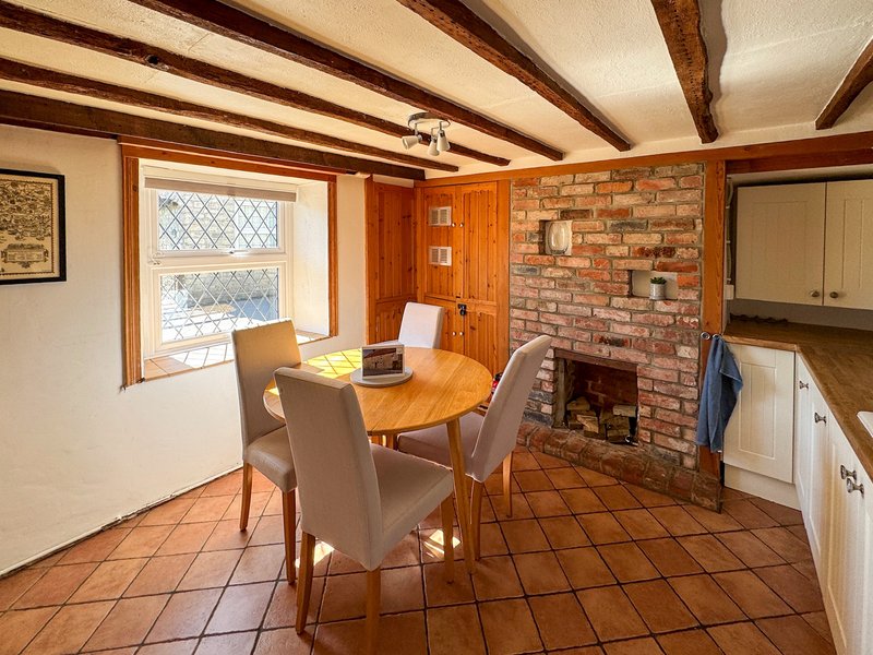 Rustic dining room with wooden beams, brick fireplace, dining table and chairs