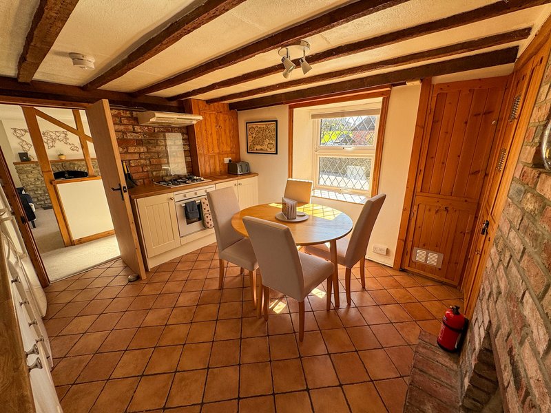 Kitchen-diner with wooden beams, brick walls, dining table, and cream appliances