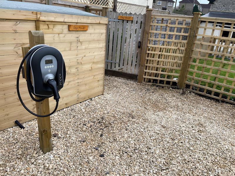 Outdoor courtyard with electric vehicle charging point mounted on wooden fence