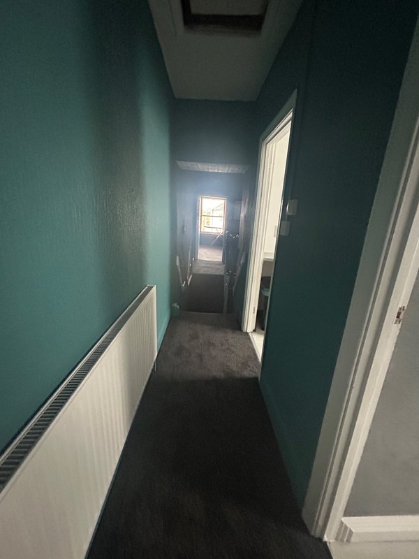 Victorian Hall way leading to bedrooms with teal walls, white baseboards, dark grey carpet and white doors