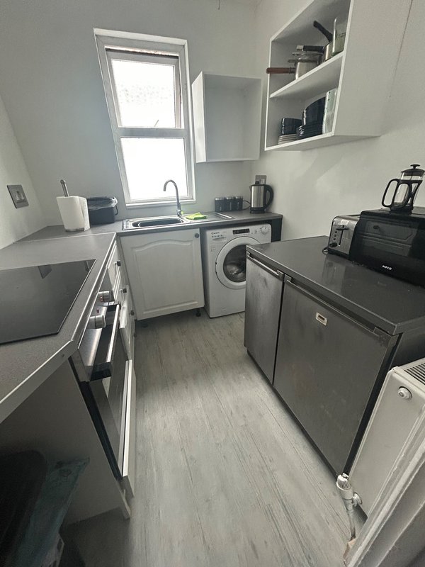 Modern kitchen with stainless steel appliances, Ninja dual airfryer, microwave, toaster, kettle and washing machine, and window overlooking garden