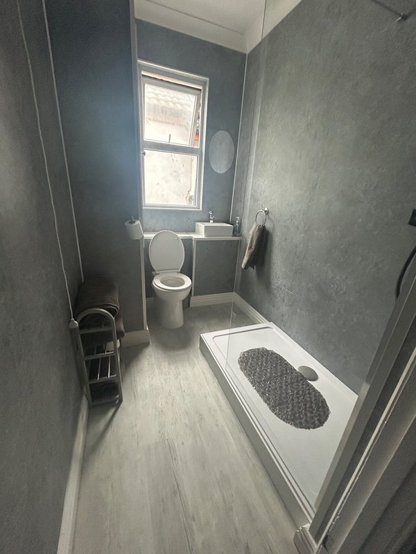 Wet room style bathroom with toilet, sink, combi boiler and window