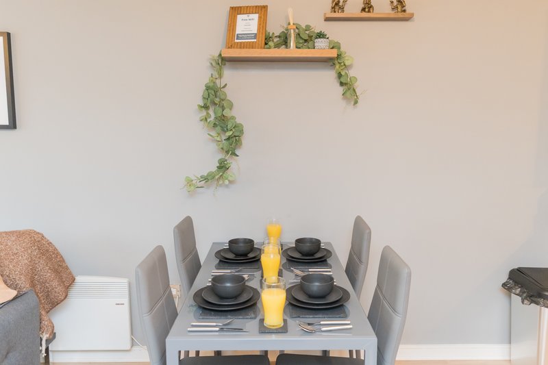 Dining table set for four with grey chairs, black place settings and yellow centrepiece
