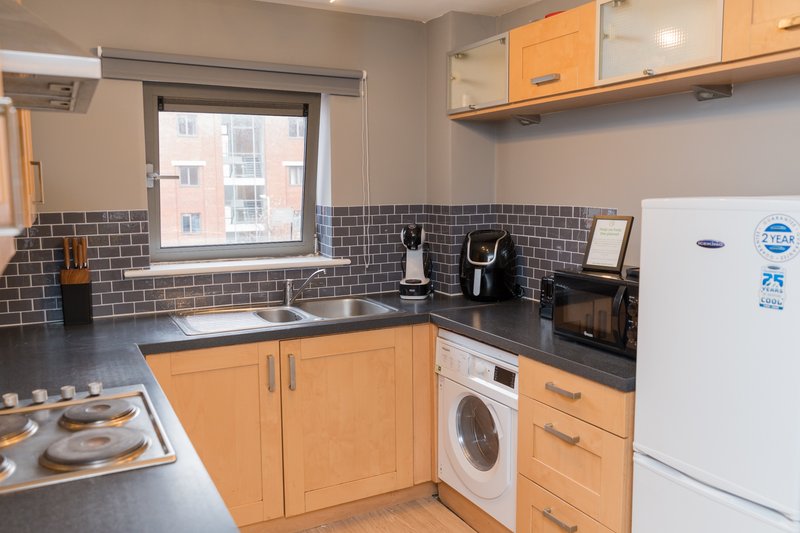 Modern kitchen with orange cabinets, black countertop, white appliances and window view