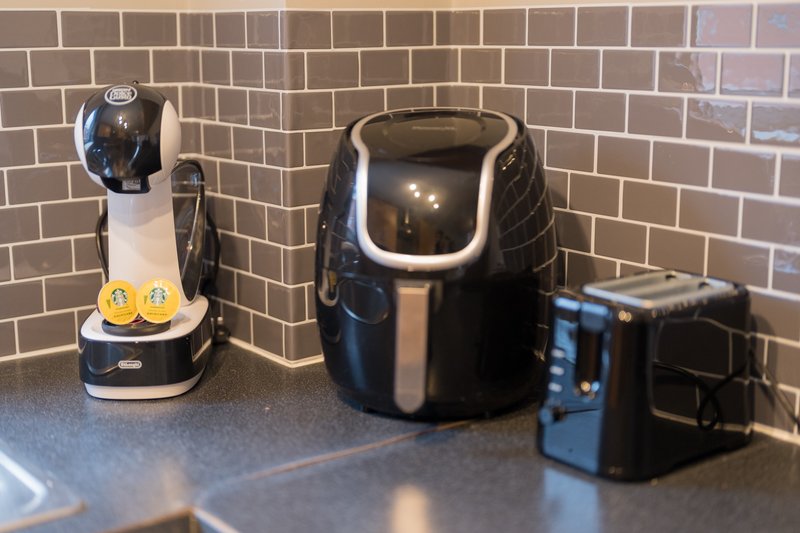 Kitchen counter with subway tile backsplash, coffee maker, air fryer, and toaster