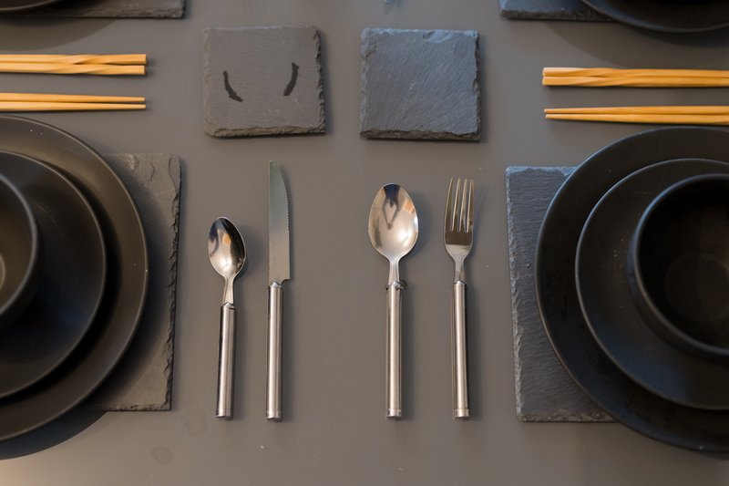 Overhead view of table setting with black plates, cutlery, slate coasters and gold trim