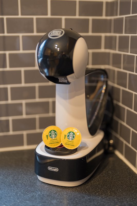 Kitchen counter with black and white Dolce Gusto coffee machine and yellow Starbucks pods