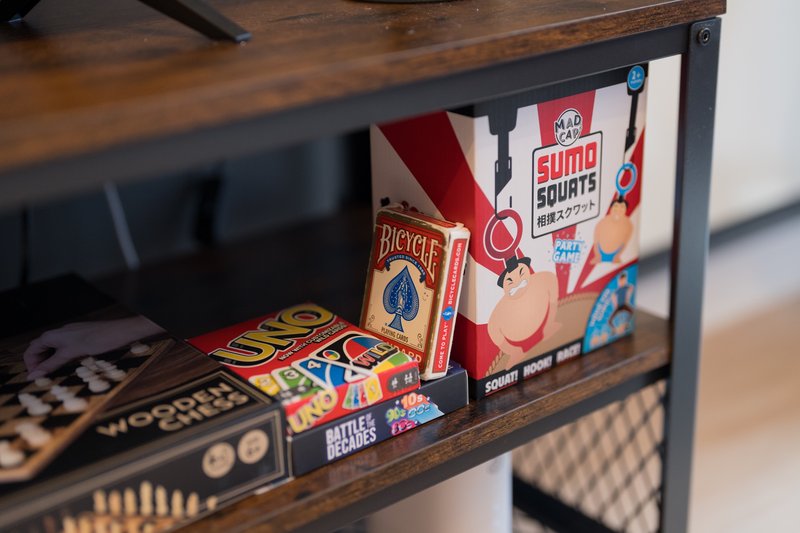 Wooden shelf with board games, playing cards, and game boxes including Bicycle and Sumo Squirts