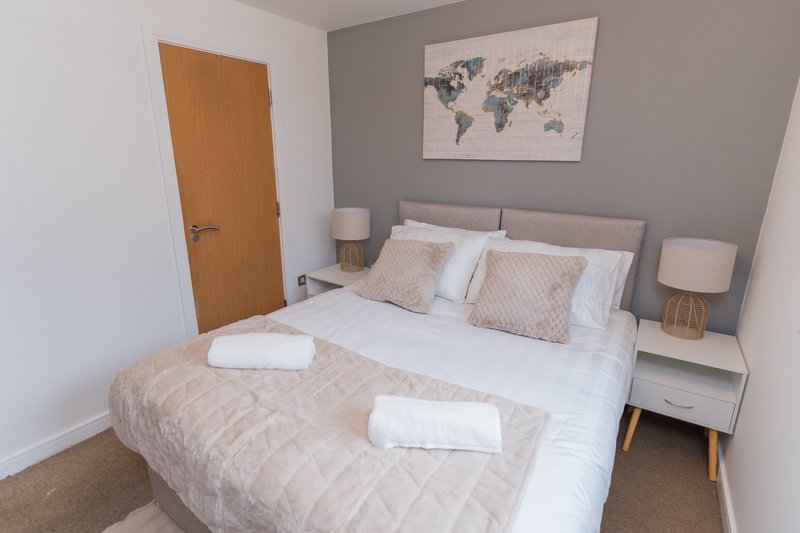 Modern bedroom with double bed, grey headboard, bedside tables, and world map wall art