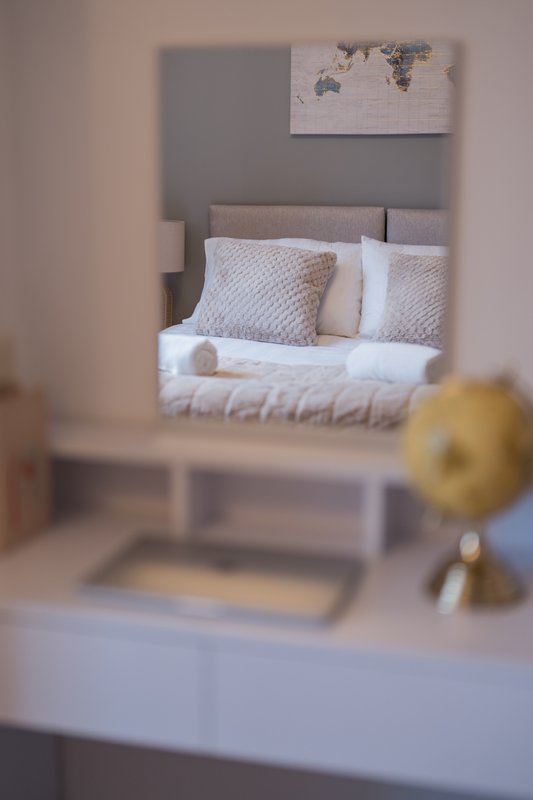 Bedroom with double bed, grey headboard, and world map wall art, viewed in mirror reflection