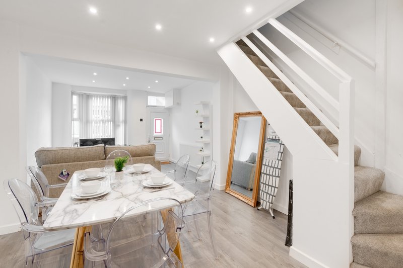 Open-plan living space with marble dining table, stairs, sofa, and modern lighting throughout