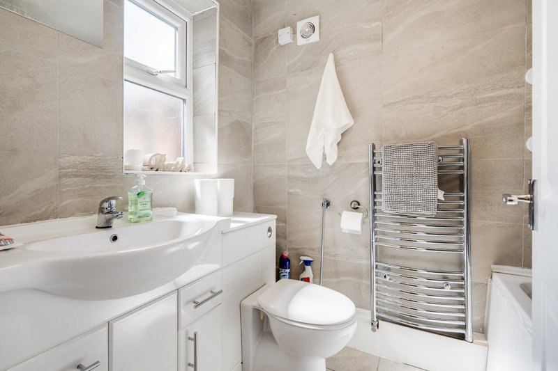 Modern bathroom with white sink, toilet, heated towel rail and window