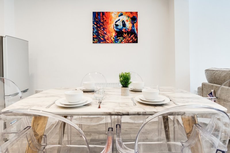 Modern dining room with marble table, clear chairs, place settings and colorful wall art