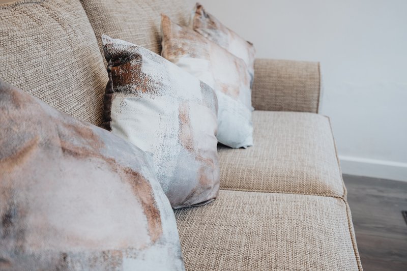 Beige upholstered sofa with decorative cushions in neutral tones