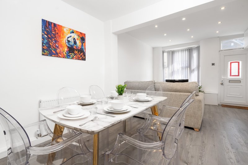 Open-plan dining and living area with marble table, transparent chairs, and sofa