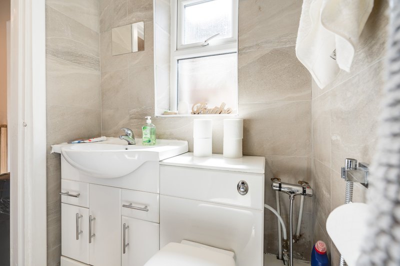 Modern bathroom with white vanity, sink, mirror, and tiled walls with window