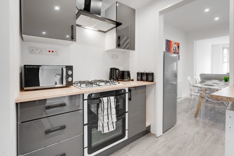 Modern kitchen with grey cabinetry, stainless steel appliances, and wooden worktops