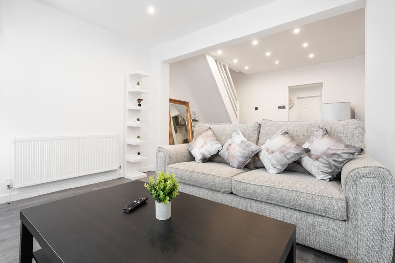 Modern living room with grey sofa, black coffee table, potted plant and recessed ceiling lights