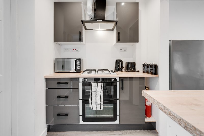 Modern kitchen with gray cabinetry, built-in oven, extractor hood, and stainless steel appliances