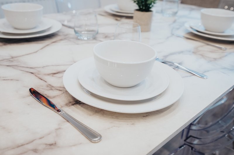 Formal dining table setting with white plates, bowls, glasses and cutlery