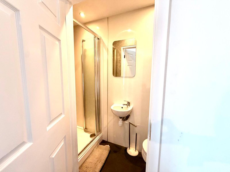 Small bathroom with shower enclosure, sink, toilet and mirror