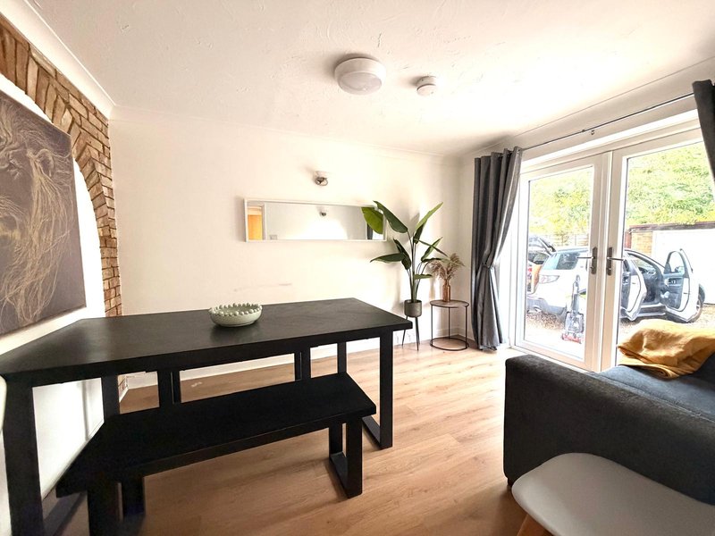 Open-plan living and dining area with black table, bench seating, and large window with garden view