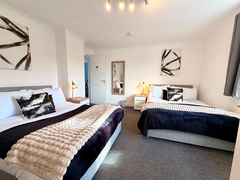 Bright bedroom with two single beds, dark bedding, artwork on walls and pendant lighting