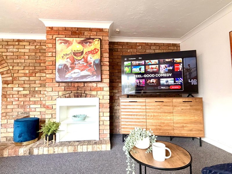 Living room with brick fireplace, TV mounted on wall, wooden media console, and round coffee table