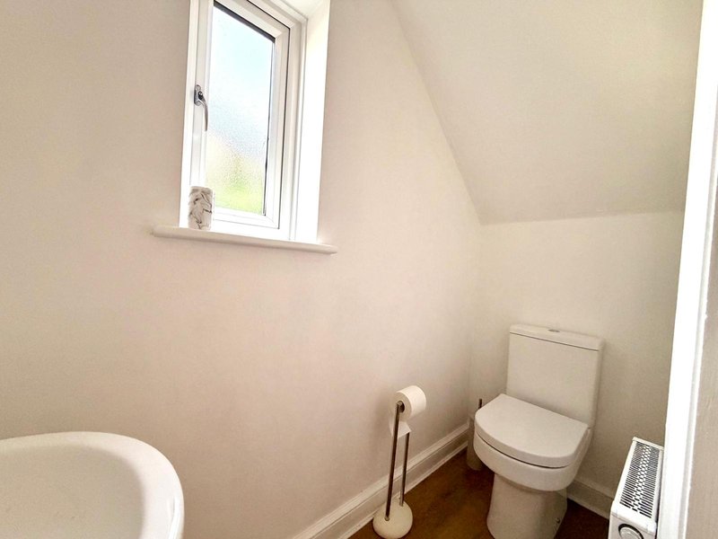 Small bathroom with toilet, sink, window and wooden floor