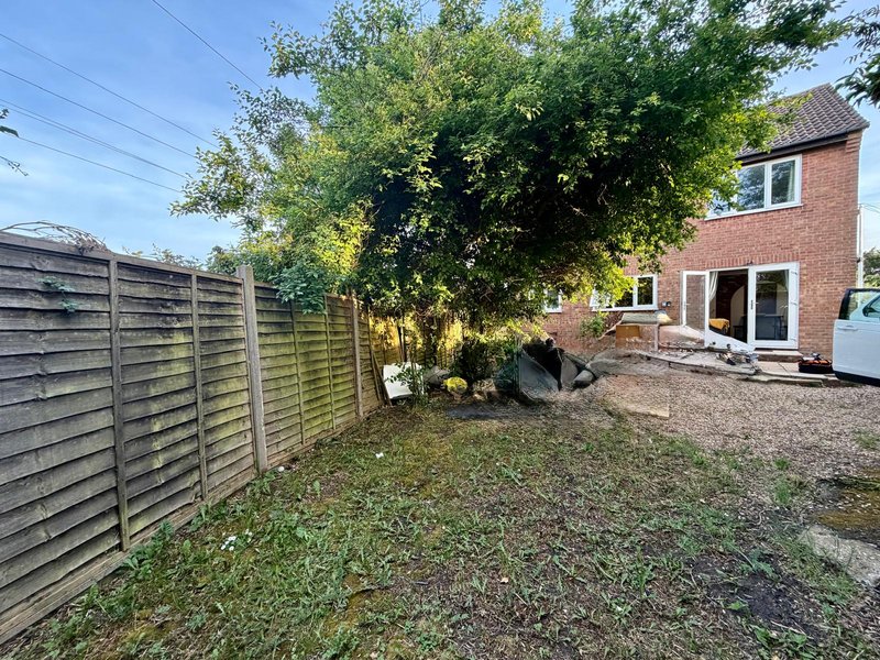 Brick house with rear garden, wooden fence, mature tree and patio area