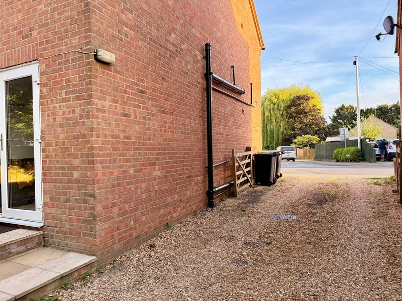 Brick property exterior with gravel driveway, side entrance door and garden area