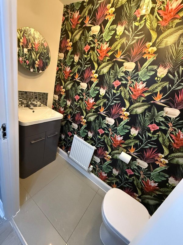 Bathroom with black vanity, toilet, sink, and tropical floral shower curtain