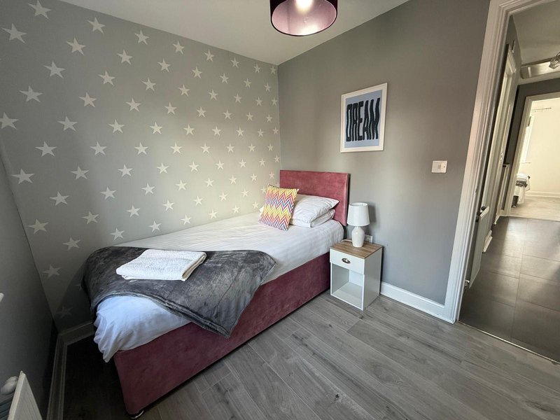 Bedroom with single bed, star-patterned wallpaper, bedside table and ceiling light