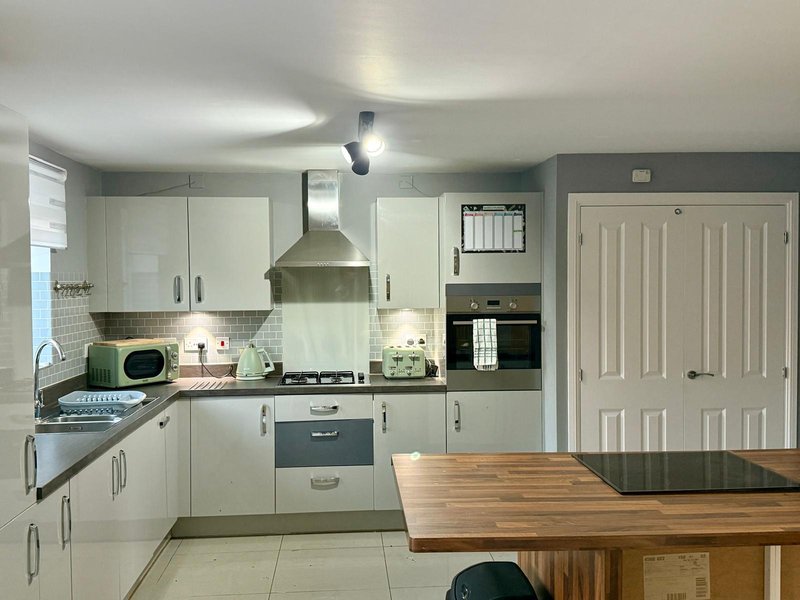 Modern kitchen with white cabinetry, stainless steel appliances, and wooden dining table