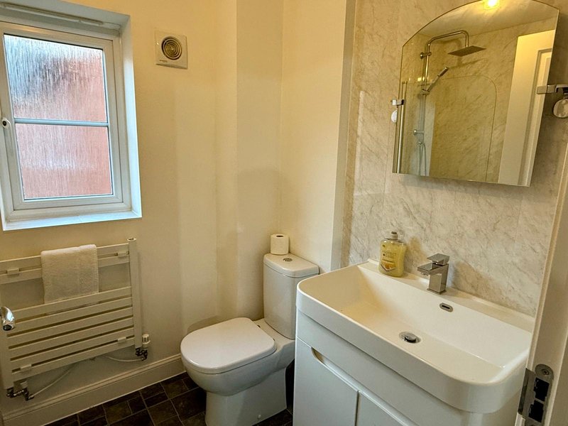 Modern bathroom with white sink vanity, toilet, heated towel rail and window