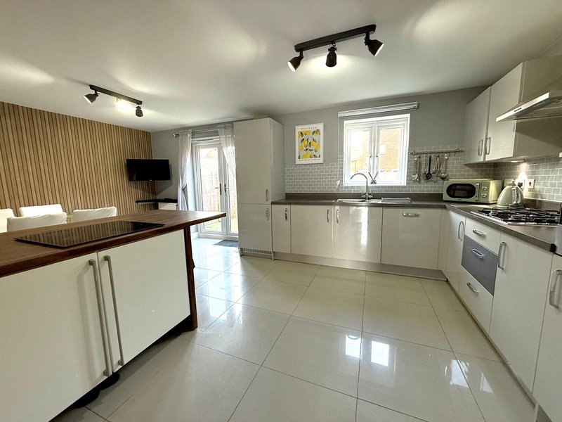 Modern open-plan kitchen and living area with white cabinetry, island counter, and tiled flooring