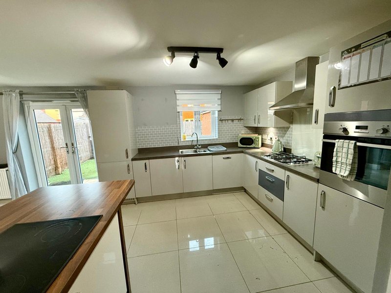 Modern kitchen with white cabinetry, stainless steel appliances, tiled floor and dining table