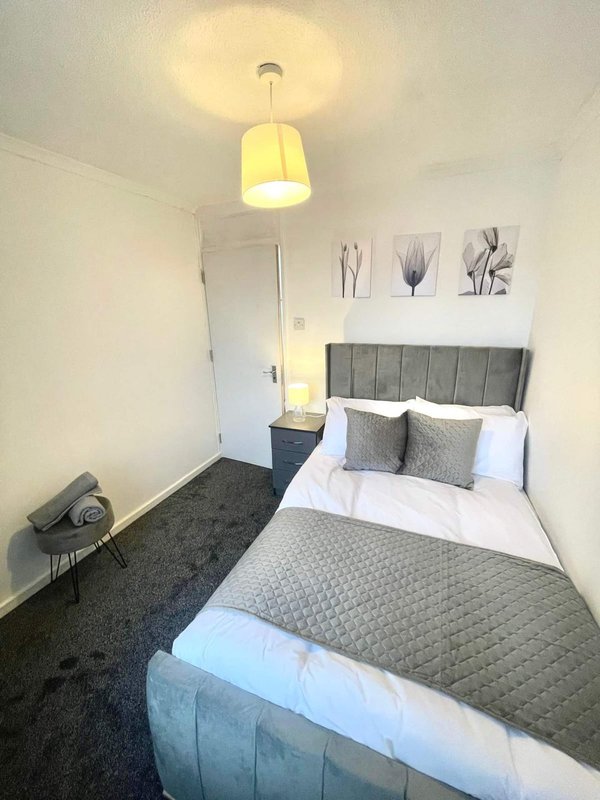 Modern bedroom with double bed, grey headboard, pendant light and framed wall art