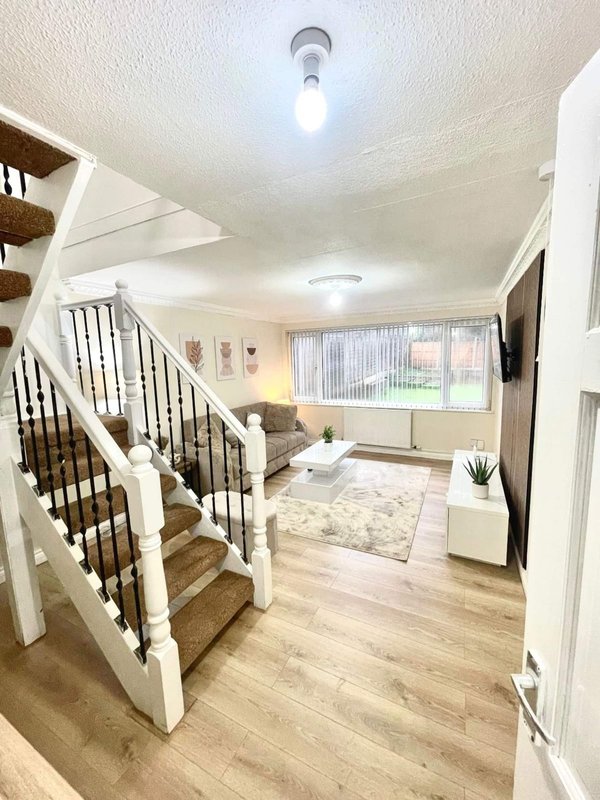 Bright staircase and landing with white bannister, wooden steps, and open-plan living area visible
