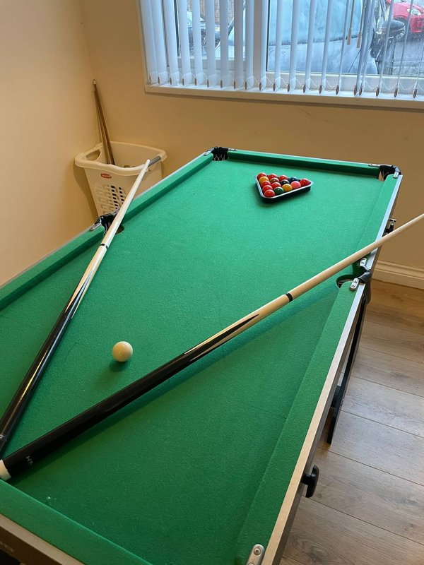 Recreation room with pool table, cues, and balls ready for play