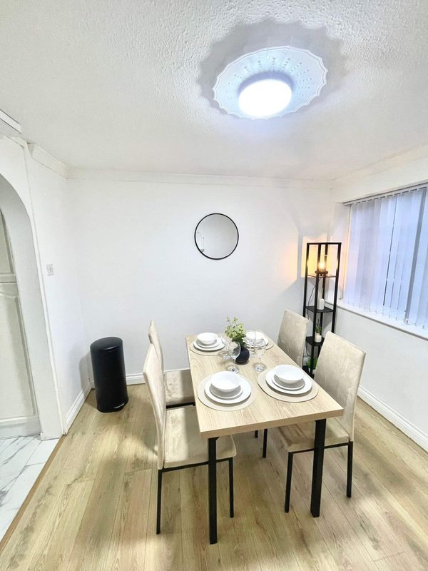 Modern dining room with wooden table, four chairs, wall clock and LED ceiling light