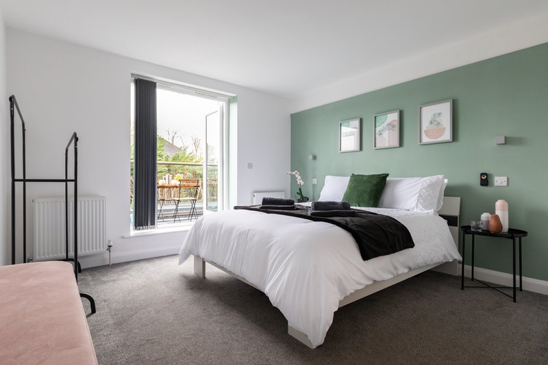 King size bed, hanging rail, ottoman storage, bedside tables, and balcony access with table and chairs. This bedroom has an en-suite shower room.