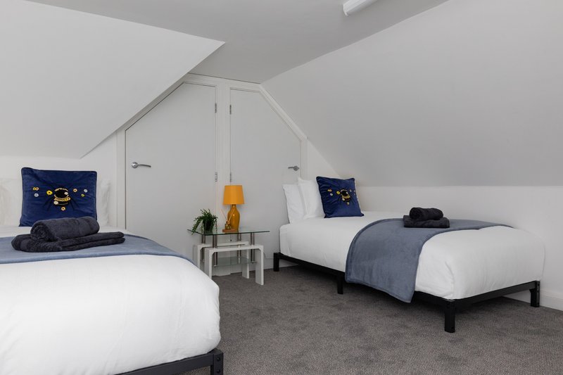 Twin bedroom with sloped ceiling with hanging rail and drawers. This is a loft room without a window, so can be warm but a fan is provided if needed.