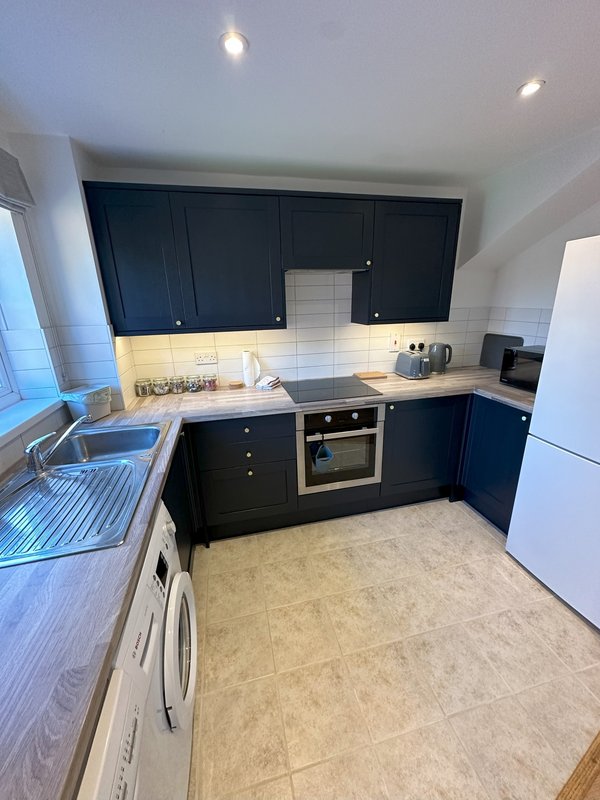 Modern kitchen with dark blue cabinets, white subway tile backsplash, stainless steel appliances and sink