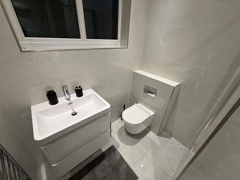 Modern bathroom with white sink, toilet, mirror and tiled walls