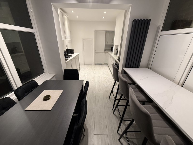 Modern shared accommodation with desk, dining table, beds and kitchen area