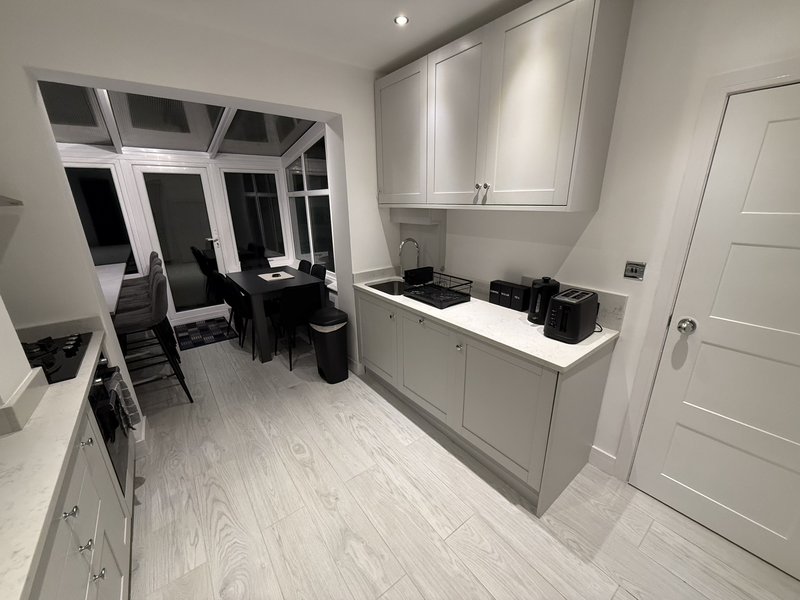 Modern open-plan kitchen and dining area with white cabinetry, light wood flooring, and dining table by windows