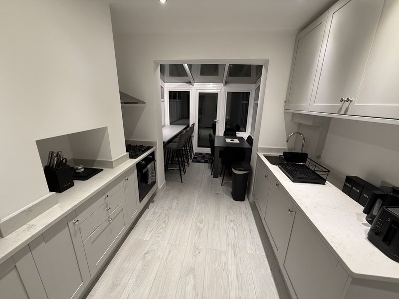 Galley kitchen with white cabinetry, light wood flooring, and garden view through French doors