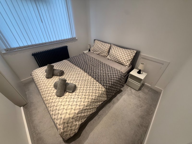 Bright modern bedroom with two beds, patterned bedding, radiator and window blinds