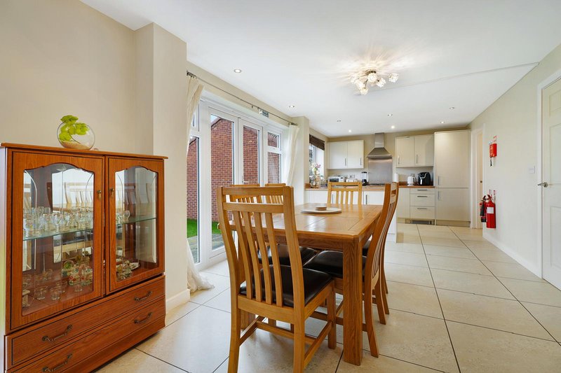Open-plan kitchen and dining area with wooden table, chairs, cabinets and cream walls